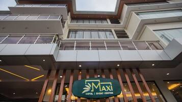 A modern building with a sign reading "MAXI HOTEL | EVENT CENTER".