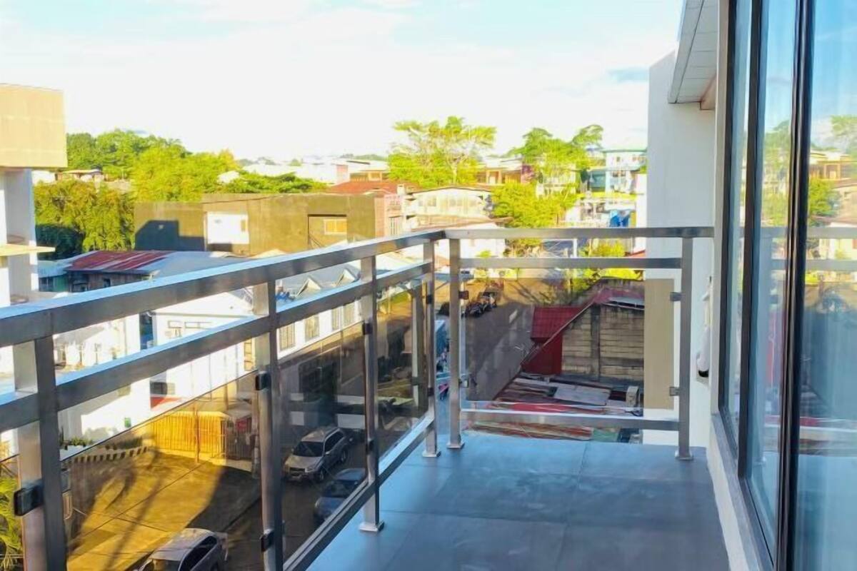 A balcony with a glass railing overlooking a residential area.