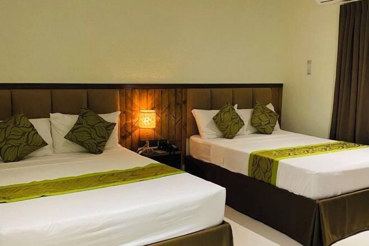 Two single beds with headboards, a nightstand with a lamp, and a window with curtains.