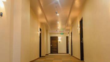 A hotel corridor with a checkered floor, doors on both sides, and overhead lighting.