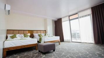 A hotel room with two beds, a large window, and a carpeted floor.