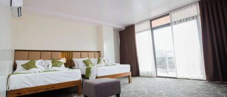 Habitación de hotel con dos camas, un ventanal grande y piso alfombrado.