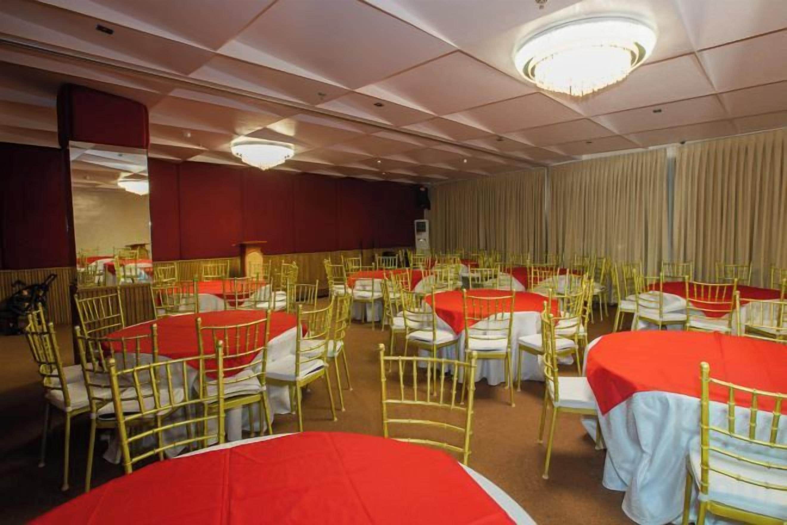 A banquet hall with round tables, chairs, and a stage.