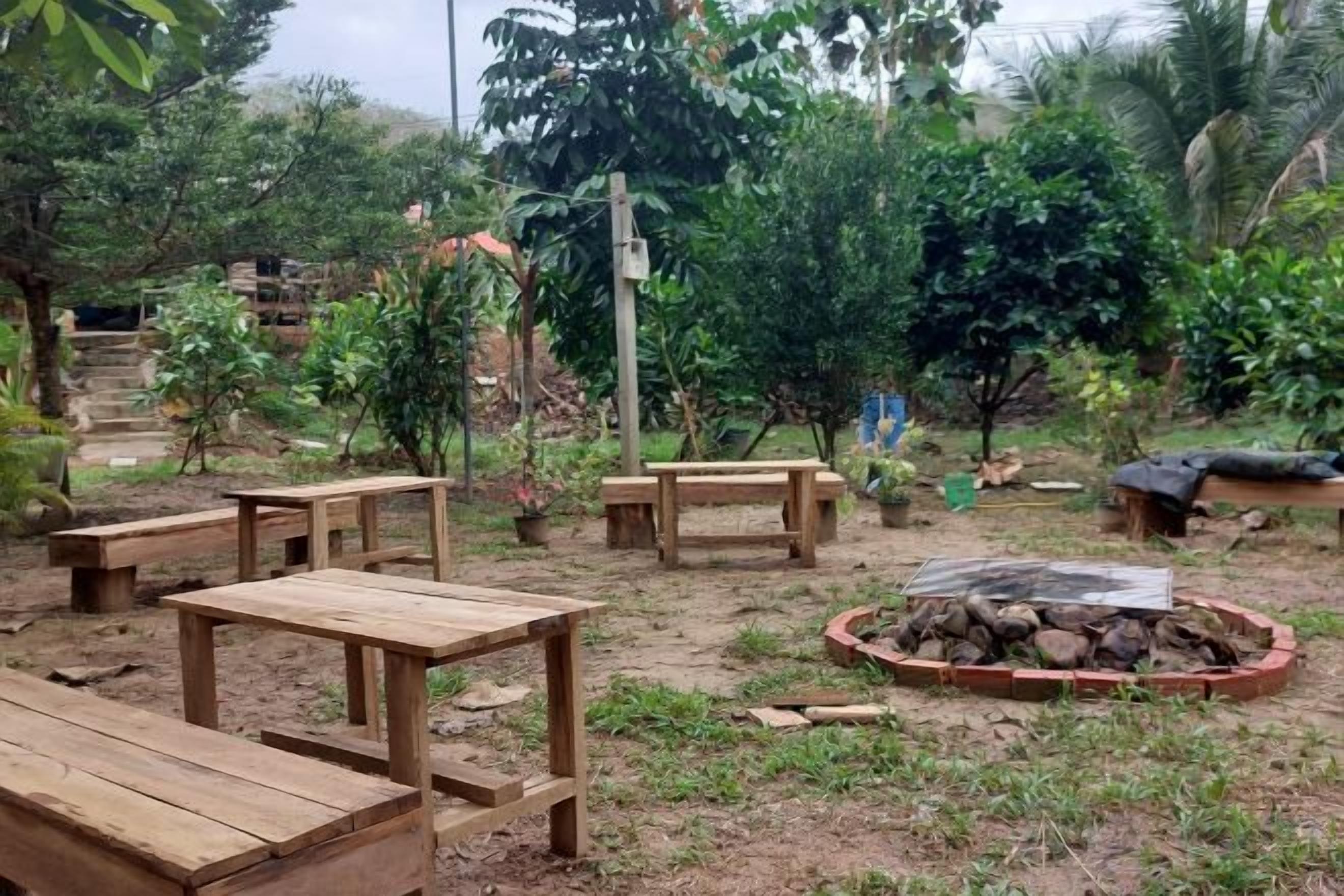 An outdoor area with wooden benches and a circular stone fire pit.