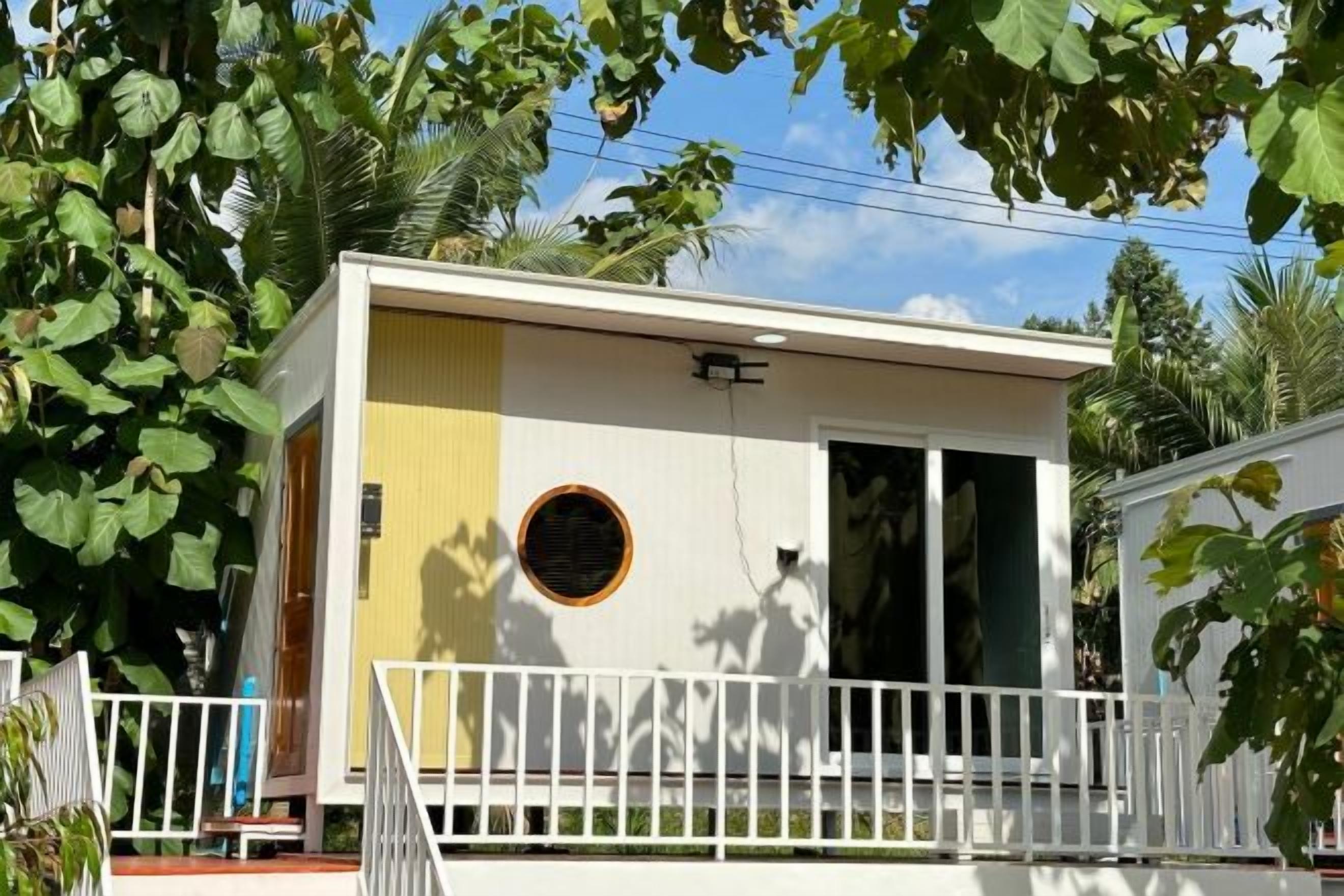 A small, single-story building with a balcony, a circular window, and a door.