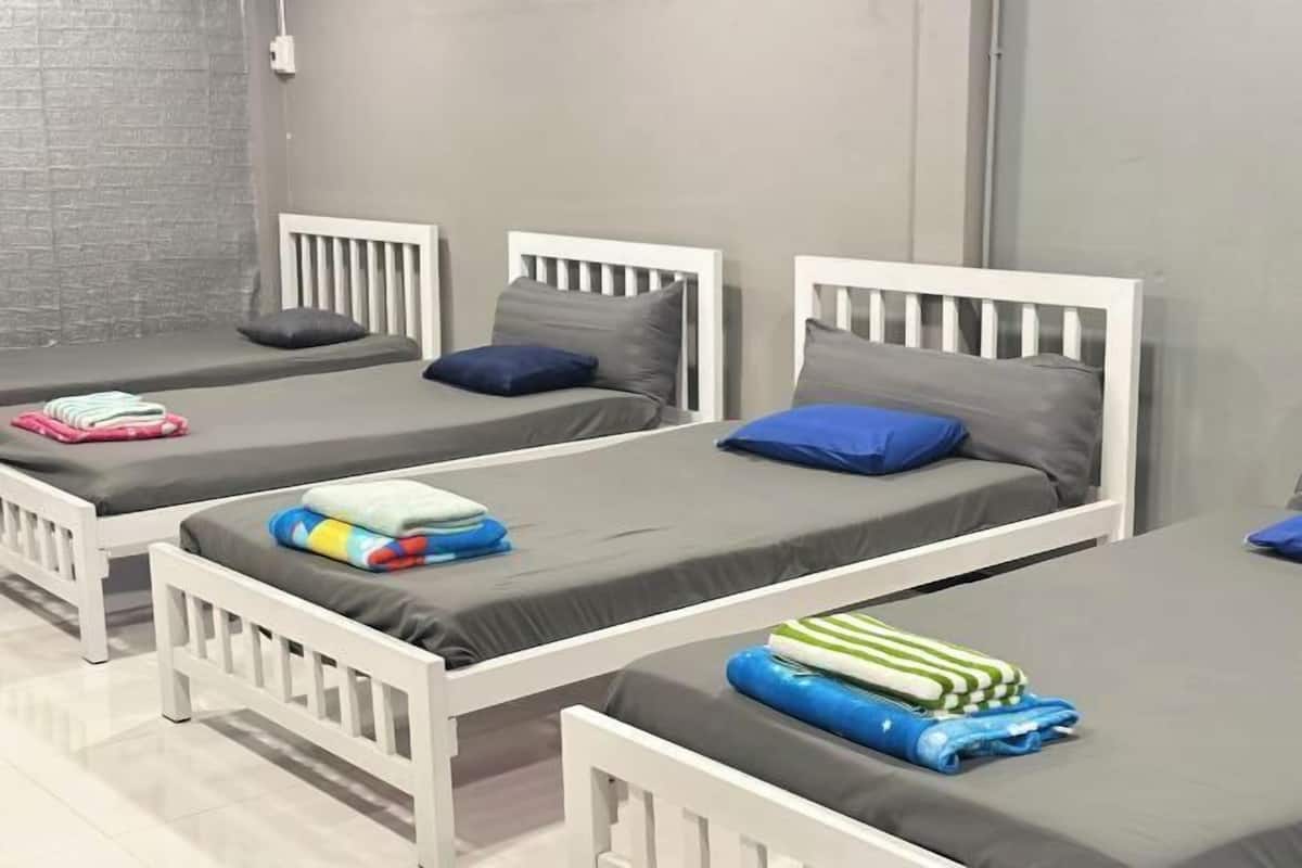 Una habitación con tres camas individuales, cada una con una almohada y un edredón doblado.