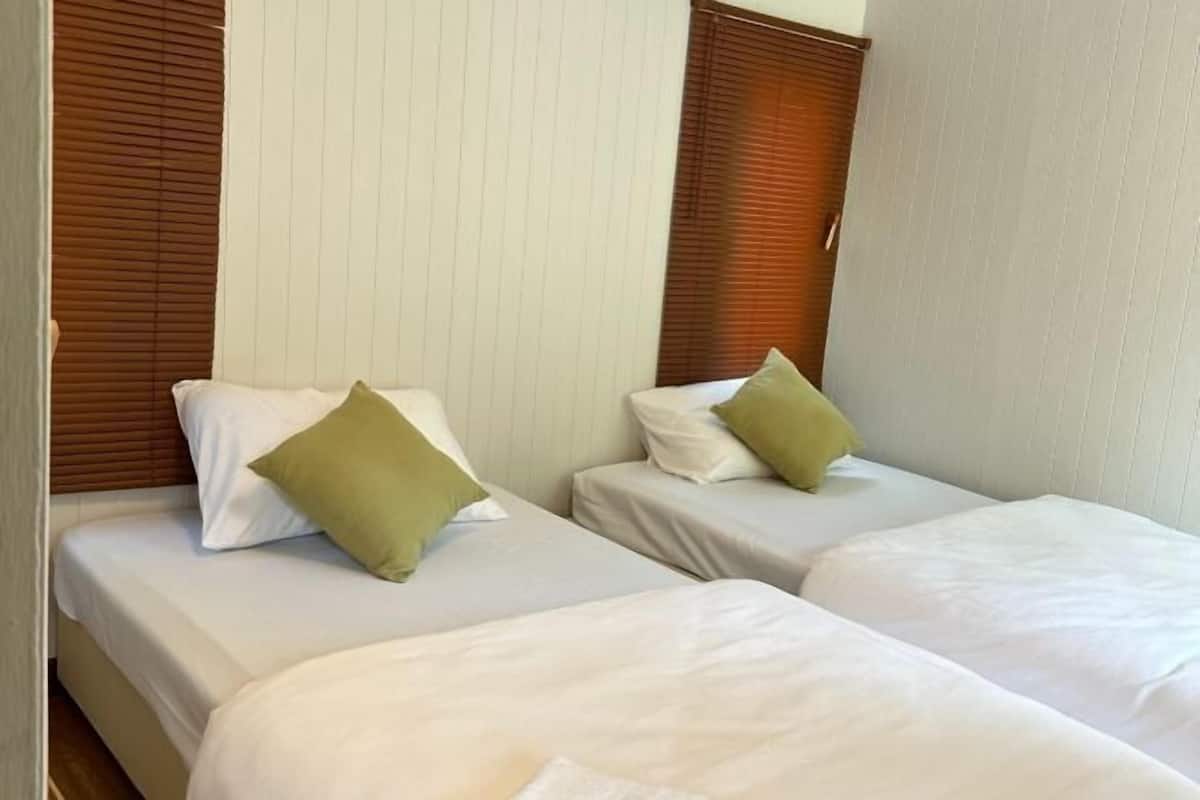 Una habitación de hotel con dos camas individuales, cada una con ropa blanca y una almohada verde.