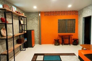 A room with a marble wall, a wooden bookshelf, a small table with stools, and an orange accent wall.