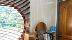 Une chambre avec un bureau en bois, une bouilloire, une bouteille d’eau et un miroir.
