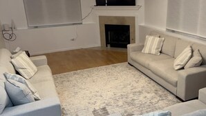A living room with a beige sofa set, a patterned rug, and a fireplace.