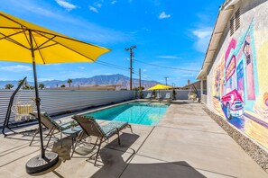 Relax by the pool surrounded by a vibrant mural and lounge chairs.