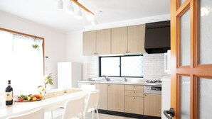 Una cocina moderna con armarios de madera clara, una campana extractora negra y un ventanal grande.