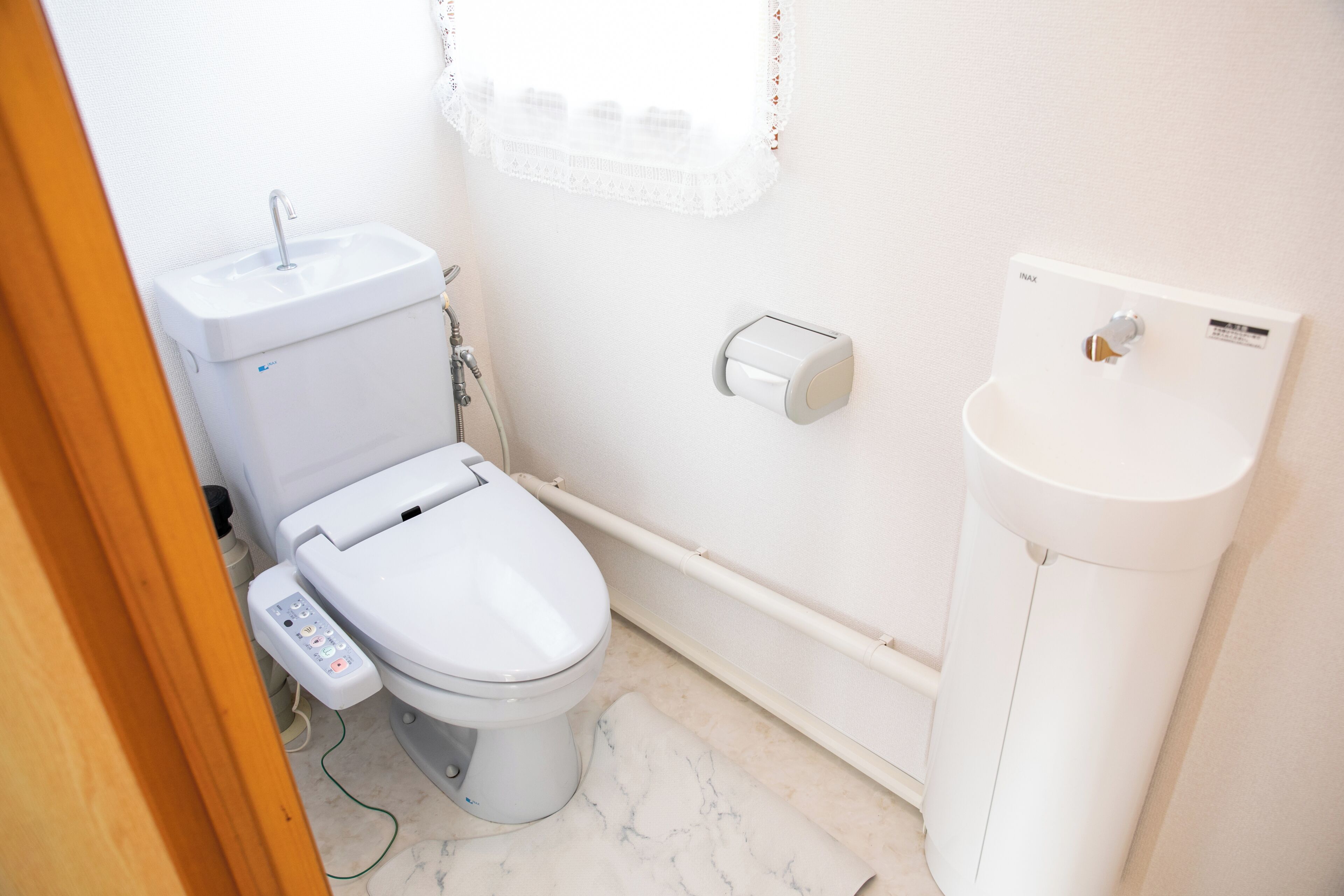 A small, modern bathroom with a toilet, bidet, and sink.
