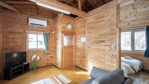Een houten chalet van binnen met een bank, televisie en een klein tafeltje.