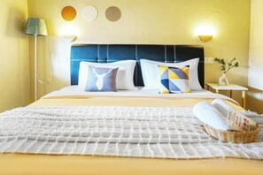 A hotel room with a bed, a bedside lamp, a nightstand with a vase, and a wall with three circular decorations.