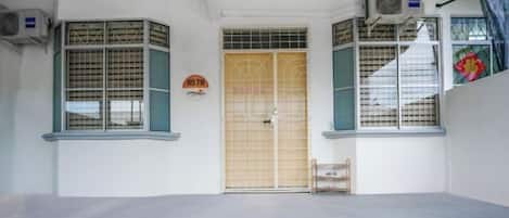 Una habitación con un ventanal grande, una puerta con placa de número y un equipo de aire acondicionado.