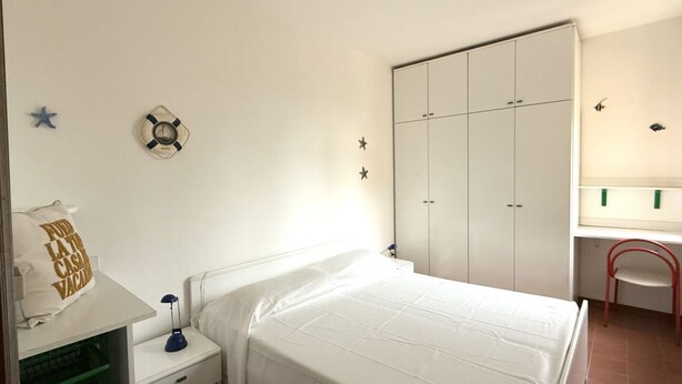 A bedroom with a bed, a nightstand, a desk, a wardrobe, and a chair. - M415 – Marcelli, three-room apartment on the ground floor with an external court (Marcelli)