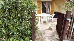 A patio with a table and chairs, a wooden gate, and a hedge. - M415 – Marcelli, three-room apartment on the ground floor with an external court (Marcelli)