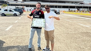 Two people standing in an open parking area with a large building in the background. - ESTACIÓN BIOLÓGICA SMF II ZONA (Indiana)