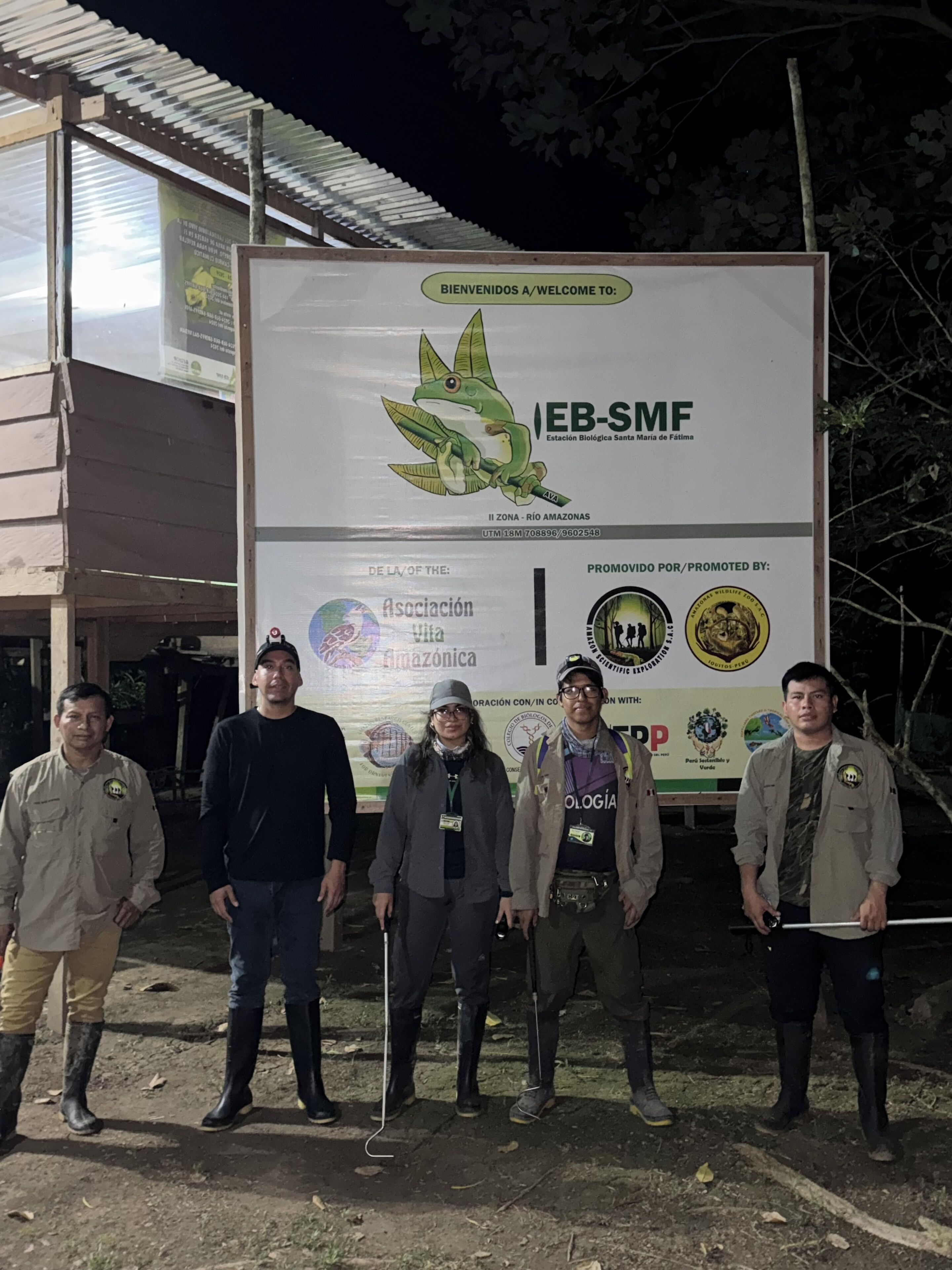 En gruppe mennesker står foran et skilt med logoer og tekst, herunder "EB-SMF" og "Asociación Amazonica".