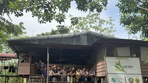 A group of people standing on a wooden platform in front of a building with a corrugated metal roof, partially submerged in water. - ESTACIÓN BIOLÓGICA SMF II ZONA (Indiana)
