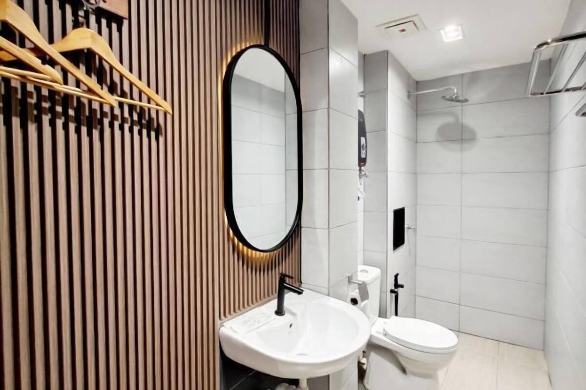 Un bagno moderno con parete rivestita in legno, un lavandino bianco, un water e uno spazio doccia.