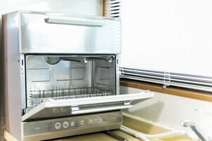 Una cocina industrial con electrodomésticos de acero inoxidable, incluyendo un horno grande y una zona de preparación de alimentos.