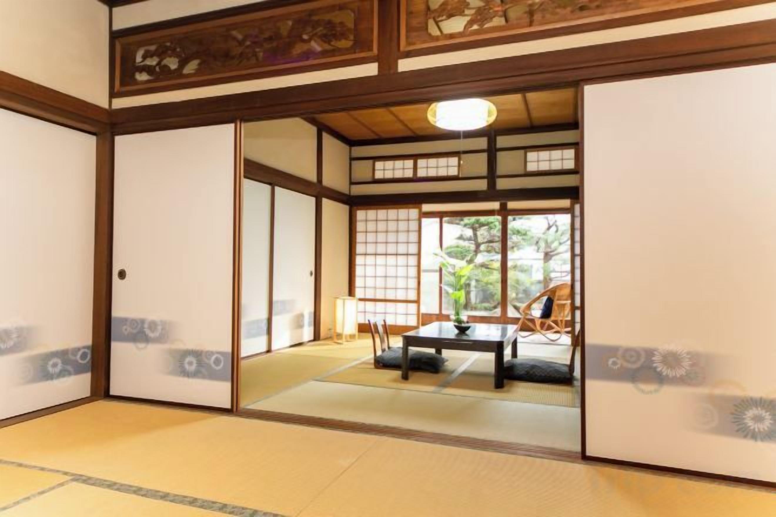 Una habitación tradicional japonesa con suelo de tatami, puertas correderas y vistas al exterior.