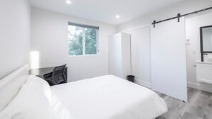 A modern bedroom with a bed, a desk, a sliding door, and a bathroom with a mirror. - Spacious 5-bed, 5-bath apartment in charming Los Angeles (Los Angeles)