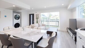 A modern kitchen with a marble countertop, a dining area with a white table and chairs, a sofa, and a large window offering a view of the outdoors. - Spacious 5-bed, 5-bath apartment in charming Los Angeles (Los Angeles)