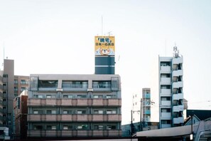 A multi-story building with a prominent yellow sign on the top. - JS Xiaozhai ・Shinimazato (Osaka)