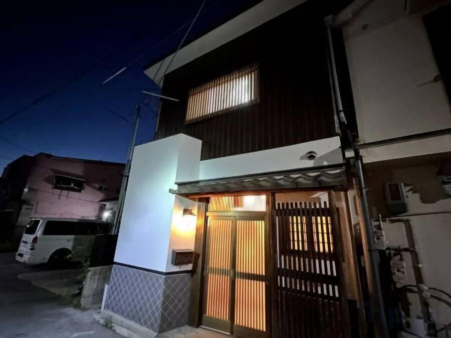 A two-story residential building with a gated entrance and a small porch area.