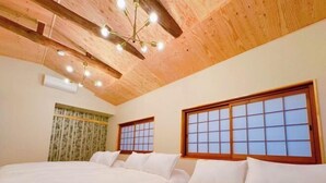 A hotel room with two beds, wooden ceiling beams, a traditional-style window, and a ceiling light fixture. - WholeHouse　Himeji (Himeji)