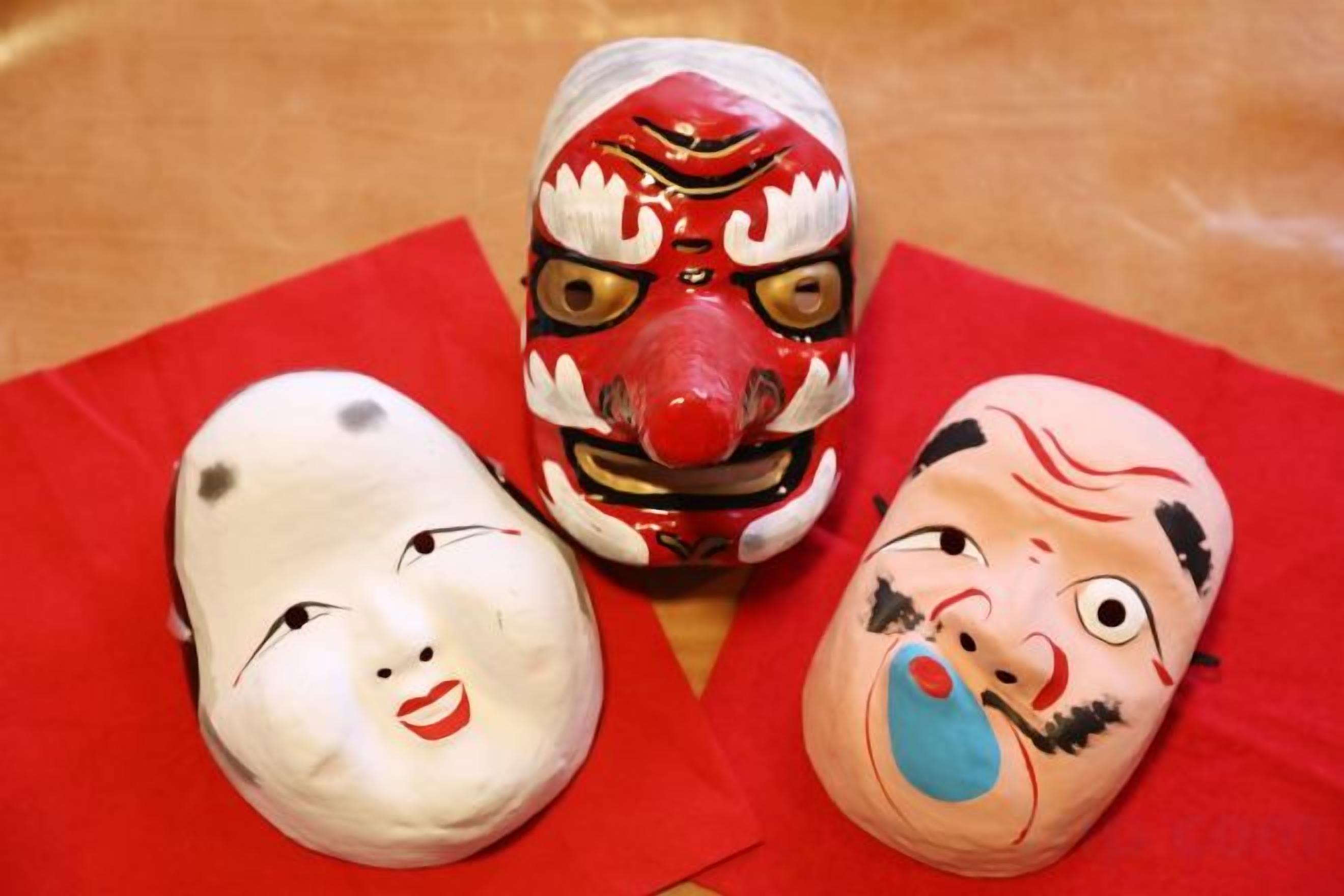 Three masks on a red cloth.