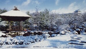 A gazebo in a snowy park with a traditional building in the background. - WholeHouse　Himeji (Himeji)