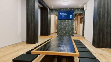A room with a tatami mat floor, a tatami mat table, and a television screen displaying 'VAST TV'.