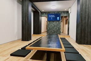 Quarto com piso e mesa de esteira de tatame, e uma tela de televisão exibindo 'VAST TV'.