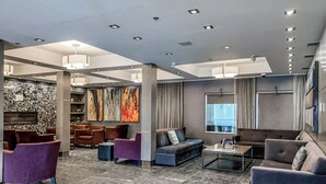 Eine moderne Lobby mit einer Steinwand, mehreren Sitzbereichen und einem großen Fenster mit Blick.