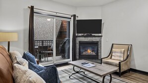 Ein Wohnzimmer mit Kamin, einer Couch, einem Sessel und einem Couchtisch.