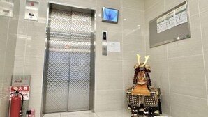 An elevator with a fire extinguisher, a digital display, and a bulletin board. - Jin Yue guesthouse (Osaka)