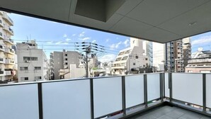 A balcony with a view of urban buildings, a tiled floor, and a metal railing. - Jin Yue guesthouse (Osaka)