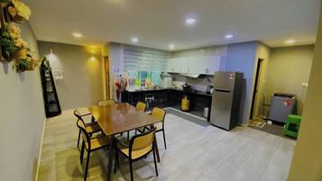 A modern kitchen with a dining table and chairs, a refrigerator, and a gas stove.
