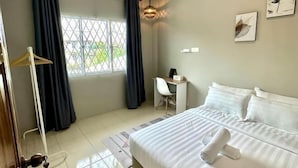 Una camera d'albergo con un letto, una scrivania, una sedia, un armadio e una finestra con tende.