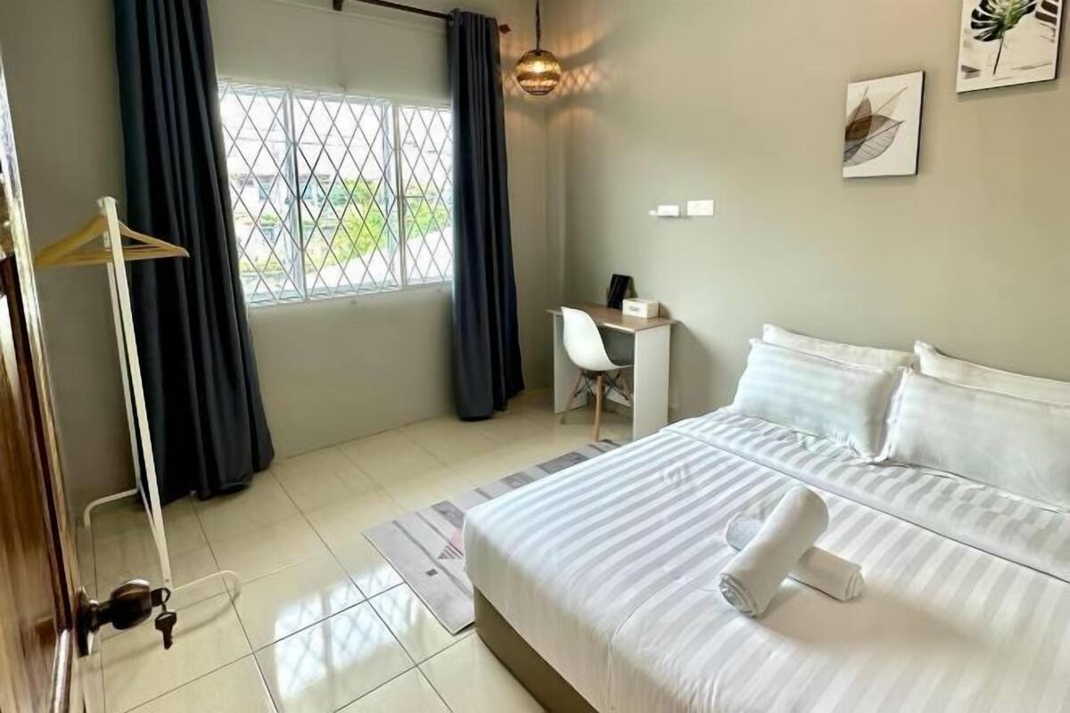 A hotel room with a bed, a desk, a chair, a wardrobe, and a window with curtains.