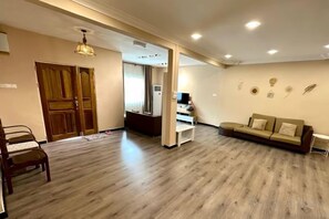 A spacious living area with a wooden floor, a sofa, a dining table, and a TV. - Ang Lee Holiday Home 2 (Semporna)