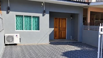 A building with a grey exterior, a wooden door, and a window with green curtains.