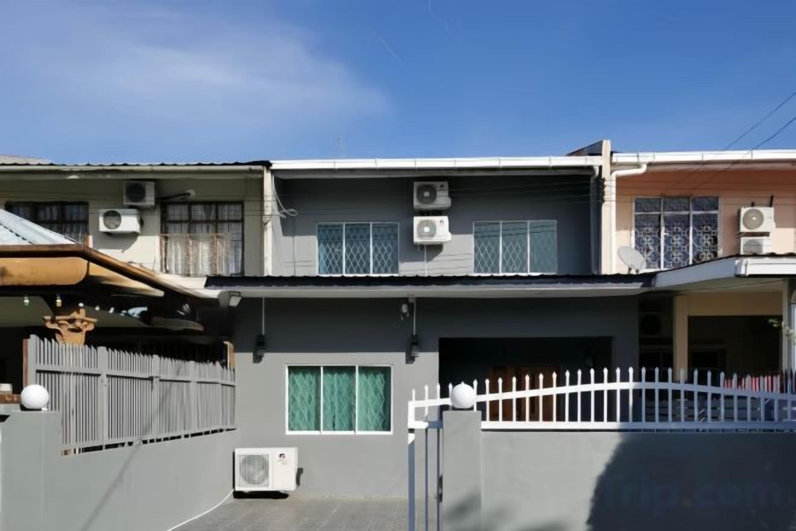 A two-story residential building with air conditioning units, a gated entrance, and a visible garage.