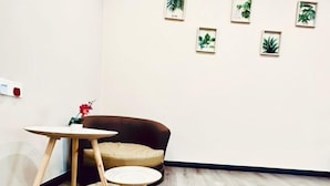 Una stanza con un divano in pelle marrone, un piccolo tavolino rotondo, un tavolo bianco e una piccola pianta in vaso.