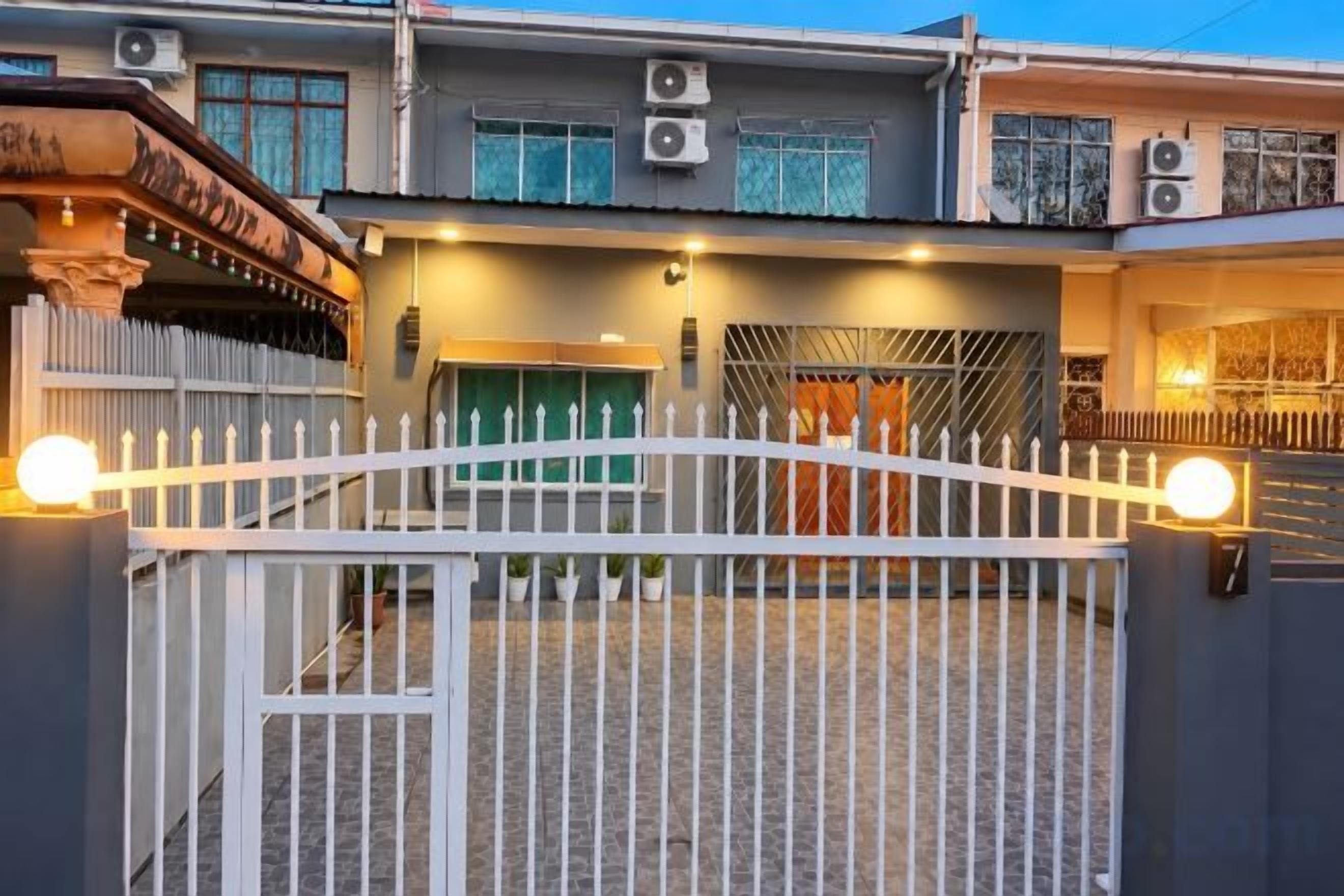 A gated residential area with a white fence, a green door, and a staircase leading to a second level.