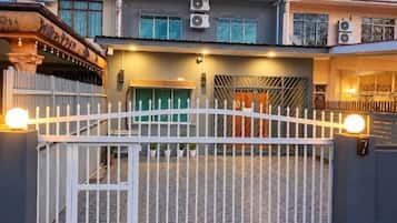 A gated residential area with a white fence, a green door, and a staircase leading to a second level.